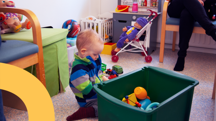 Ett barn leker på golvet bredvid en stor leksakslåda.