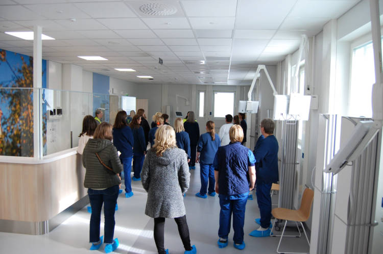 På bilden står sjukhuspersonal med ryggen mot kameran, det finns en väggmålning på väggen i rummet.
