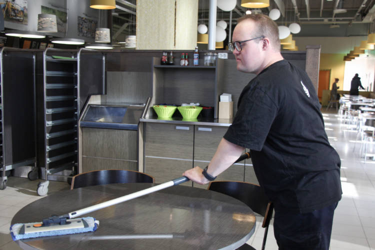 Vammainen henkilö putsaa pöytiä ravintolassa.