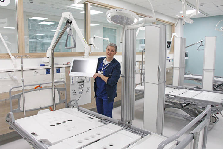 Sjuksköterskan visar datorskärmen bredvid patientens säng.