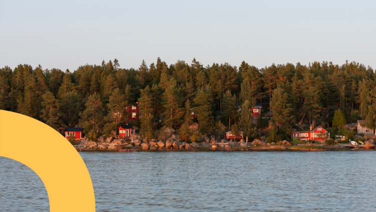 Kuvassa näkyy saaristomiljöö, jossa on merta ja kivikkoinen ranta sekä punaisia mökkejä havupuiden lomassa.