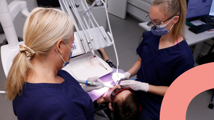 Hammaslääkäri ja hammashoitaja hoitavat tuolissa makaavan potilaan hampaita
