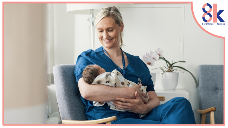 En ljushårig kvinna klädd i blå sjukskötarkläder sitter med en bebis i famnen. Hon ser ner på bebisen och ler.